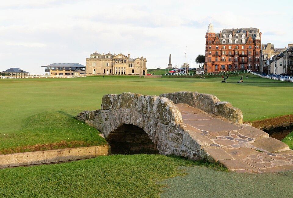 Swilcan bridge, St Andrews Old Course, with  the Royal & Ancient Clubhouse and Hamilton Grand behind. Photo: Gordon Hatton  CC BY-SA 2.0 This file is licensed under the Creative Commons Attribution-Share Alike 2.0 Generic license.