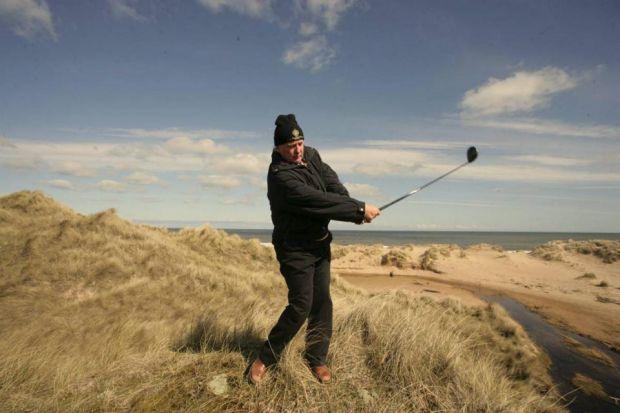 Real estate tycoon Donald Trump practices his golf swing on the Menie dunes. Photo courtesy of Herald Scotland