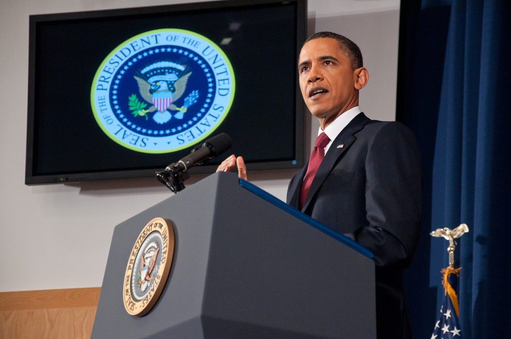 President Barack Obama with presidential seal. Photo: National Defense University. This file is licensed under the Creative Commons Attribution 2.0 Generic license.